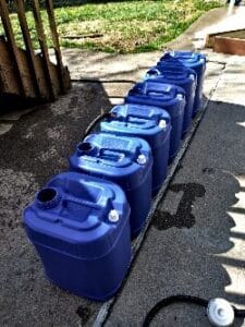 Jack Filling Water Jugs In Backyard